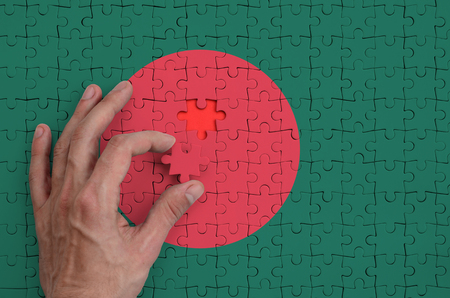 Bangladesh flag  is depicted on a puzzle, which the man's hand completes to fold.の写真素材