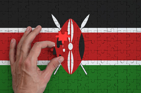 Kenya flag  is depicted on a puzzle, which the man's hand completes to fold.の写真素材