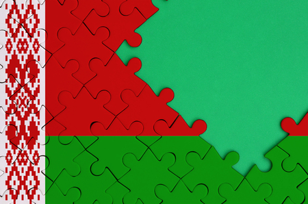 Belarus flag  is depicted on a completed jigsaw puzzle with free green copy space on the right side.の写真素材