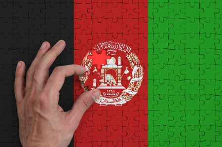 Afghanistan flag is depicted on a puzzle, which the man's hand completes to fold.の写真素材