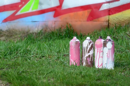 A few used paint cans lie on the ground near the wall with a beautiful graffiti painting. Street art and vandalism concept.の写真素材