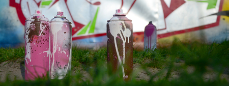 A few used paint cans lie on the ground near the wall with a beautiful graffiti painting. Street art and vandalism concept.の写真素材