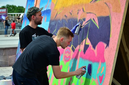 KHARKOV, UKRAINE - MAY 27, 2017: Festival of street arts. Young guys draw graffiti on portable wooden walls in the center of the city. The process of painting on walls with aerosol spray cansのeditorial素材