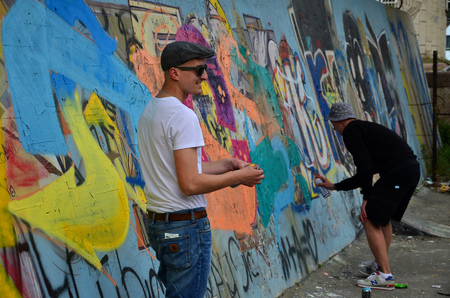 KHARKOV, UKRAINE - MAY 27, 2017: Festival of street arts. Young guys draw graffiti on an old concrete walls in the center of the city. The process of painting on walls with aerosol spray cansのeditorial素材