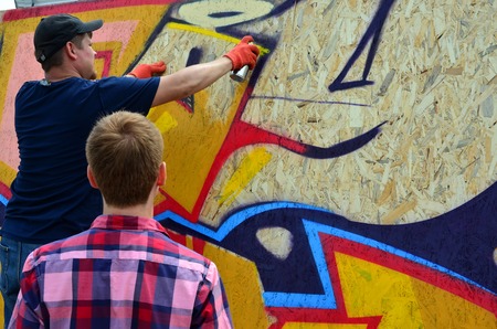 KHARKOV, UKRAINE - MAY 27, 2017: Festival of street arts. Young guys draw graffiti on portable wooden walls in the center of the city. The process of painting on walls with aerosol spray cansのeditorial素材