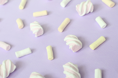 Colorful marshmallow laid out on violet paper background. pastel creative textured pattern. Perspective macro shot.の写真素材