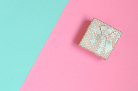 Small pink gift box lie on texture background of fashion pastel blue and pink colors paper in minimal concept.の写真素材