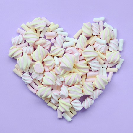 Colorful marshmallow laid out on violet and pink paper background. pastel creative textured heart. minimal.の写真素材