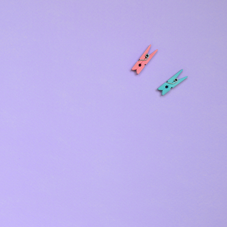 Two colored wooden pegs lie on texture background of fashion pastel violet color paper in minimal concept.の写真素材