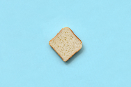 A piece of bread lies on texture background of fashion pastel blue color paper in minimal concept.の写真素材