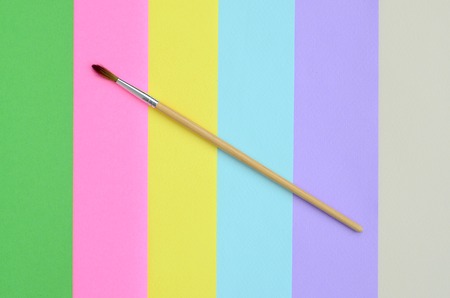 A new paint brush lie on texture background of fashion pastel pink, blue, green, yellow, violet and beige colors paper in minimal concept. Abstract trendy pattern.の写真素材