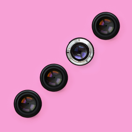 A few camera lenses with a closed aperture lie on texture background of fashion pastel pink color paper in minimal concept. Abstract trendy pattern.の写真素材