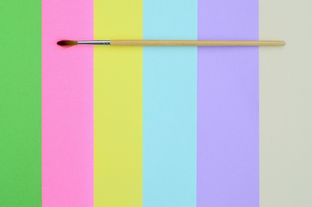 A new paint brush lie on texture background of fashion pastel pink, blue, green, yellow, violet and beige colors paper in minimal concept. Abstract trendy pattern.の写真素材