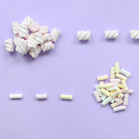 Colorful marshmallow laid out on violet paper background. pastel creative texture. minimal.