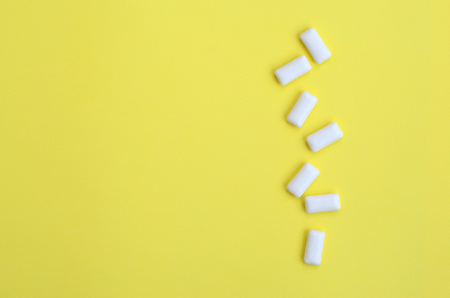 A few chewing gums lie on texture background of fashion pastel yellow color paper in minimal concept.の写真素材