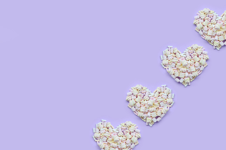 Colorful marshmallow laid out on violet and pink paper background. pastel creative textured hearts. minimal.の写真素材