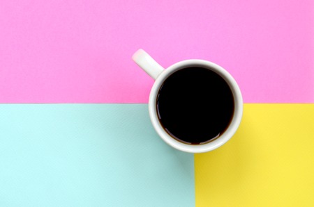 Small white coffee cup on texture background of fashion pastel blue, yellow and pink colors paper in minimal concept.の写真素材