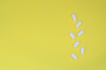 A few chewing gums lie on texture background of fashion pastel yellow color paper in minimal concept.の写真素材
