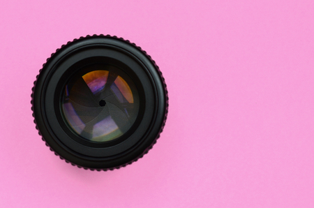 Camera lens with a closed aperture lie on texture background of fashion pastel pink color paper in minimal concept.の写真素材