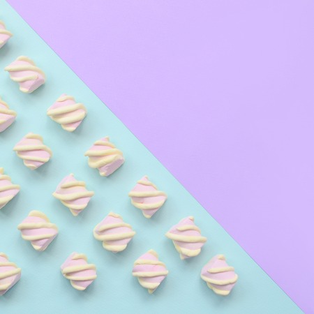 Colorful marshmallow laid out on violet and blue paper background. pastel creative textured pattern. minimal.の写真素材
