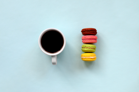 Colorful dessert cake macaron or macaroon and coffee cup on trendy pastel blue background top view. Flat lay composition.の写真素材