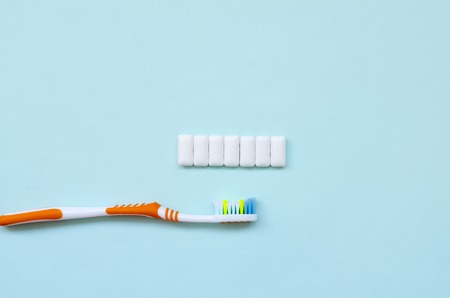 Toothbrush and chewing gums lie on a pastel blue background. Top view, flat lay. Minimal concept.の写真素材