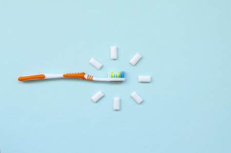 Toothbrush and chewing gums lie on a pastel blue background. Top view, flat lay. Minimal concept.の写真素材