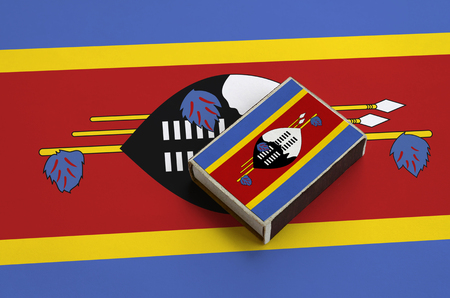 Swaziland flag  is pictured on a matchbox that lies on a large flag.の写真素材