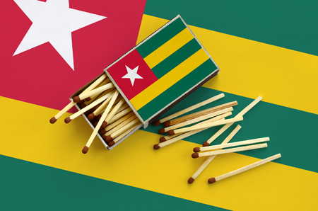 Togo flag  is shown on an open matchbox, from which several matches fall and lies on a large flag.の写真素材