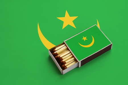 Mauritania flag  is shown in an open matchbox, which is filled with matches and lies on a large flag.の写真素材