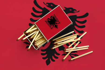 Albania flag  is shown on an open matchbox, from which several matches fall and lies on a large flag.の写真素材
