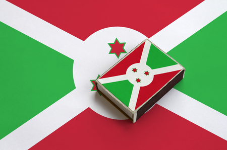 Burundi flag  is pictured on a matchbox that lies on a large flag.の写真素材