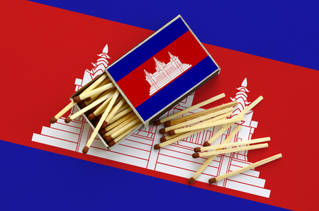 Cambodia flag  is shown on an open matchbox, from which several matches fall and lies on a large flag.の写真素材