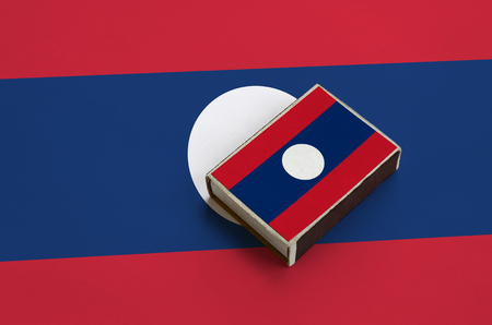 Laos flag  is pictured on a matchbox that lies on a large flag.の写真素材