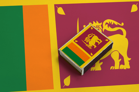 Sri Lanka flag  is pictured on a matchbox that lies on a large flag.の写真素材