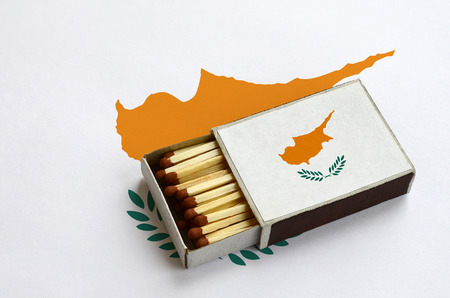 Cyprus flag  is shown in an open matchbox, which is filled with matches and lies on a large flag.の写真素材