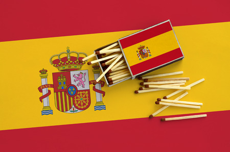 Spain flag  is shown on an open matchbox, from which several matches fall and lies on a large flag.の写真素材