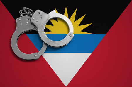 Antigua and Barbuda flag  and police handcuffs. The concept of crime and offenses in the country.の写真素材