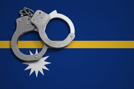 Nauru flag  and police handcuffs. The concept of crime and offenses in the country.の写真素材