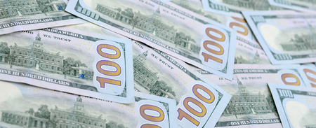 A large number of US dollar bills of a new design with a blue stripe in the middle. Top view.