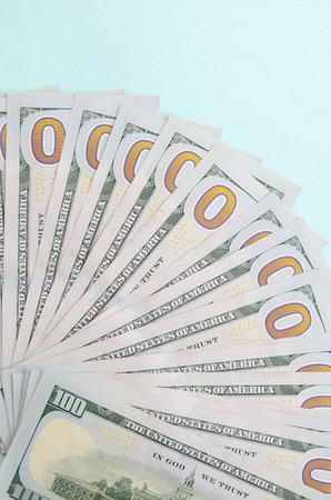 Fan of a US dollar bills of a new design lies on a light blue background.