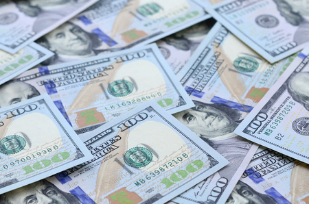 A large number of US dollar bills of a new design with a blue stripe in the middle. Top view.