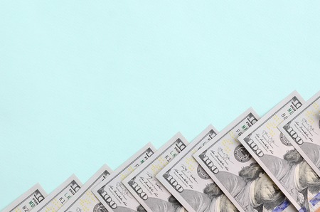 Row of a US dollar bills of a new design lies on a light blue background.