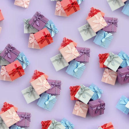 Piles of a small colored gift boxes with ribbons lies on a violet background. Minimalism flat lay top view pattern.の写真素材