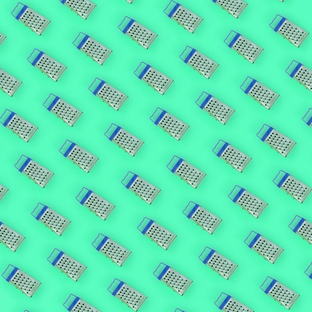 Small stainless steel graters lies on a pastel colored paper. Kitchen accessories. Tools for cooking. Flat lay top view.の写真素材