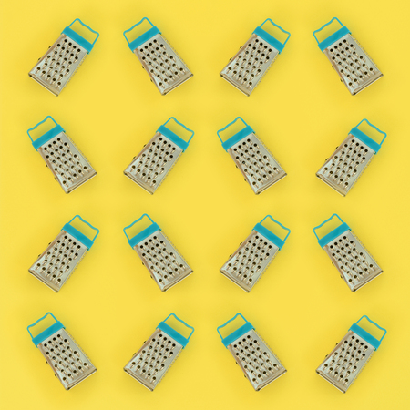 Small stainless steel graters lies on a pastel colored paper. Kitchen accessories. Tools for cooking. Flat lay top view.の写真素材