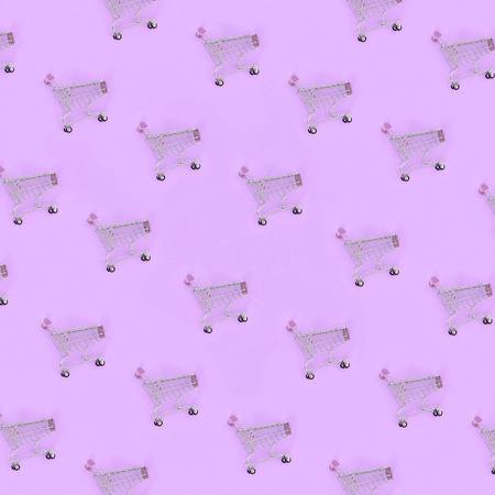 Shopping addiction, shopping lover or shopaholic concept. Many small empty shopping carts perform a pattern on a pastel colored paper background. Flat lay composition, top view.の写真素材