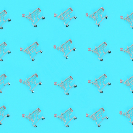 Shopping addiction, shopping lover or shopaholic concept. Many small empty shopping carts perform a pattern on a pastel colored paper background. Flat lay composition, top view.の写真素材