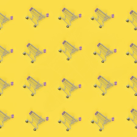 Shopping addiction, shopping lover or shopaholic concept. Many small empty shopping carts perform a pattern on a pastel colored paper background. Flat lay composition, top view.の写真素材