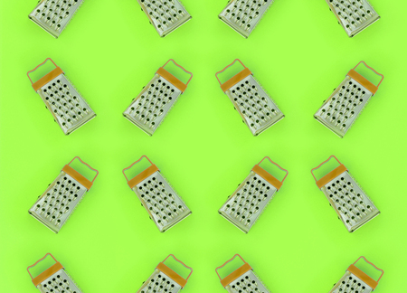 Small stainless steel graters lies on a pastel colored paper. Kitchen accessories. Tools for cooking. Flat lay top view.の写真素材